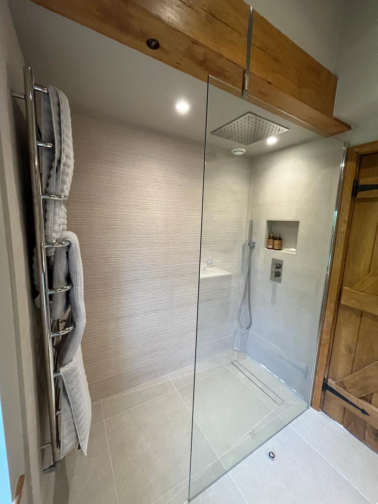 Modern wetroom with frameless glass shower screen and ceiling-mounted waterfall shower head in Exeter SBR Property Services